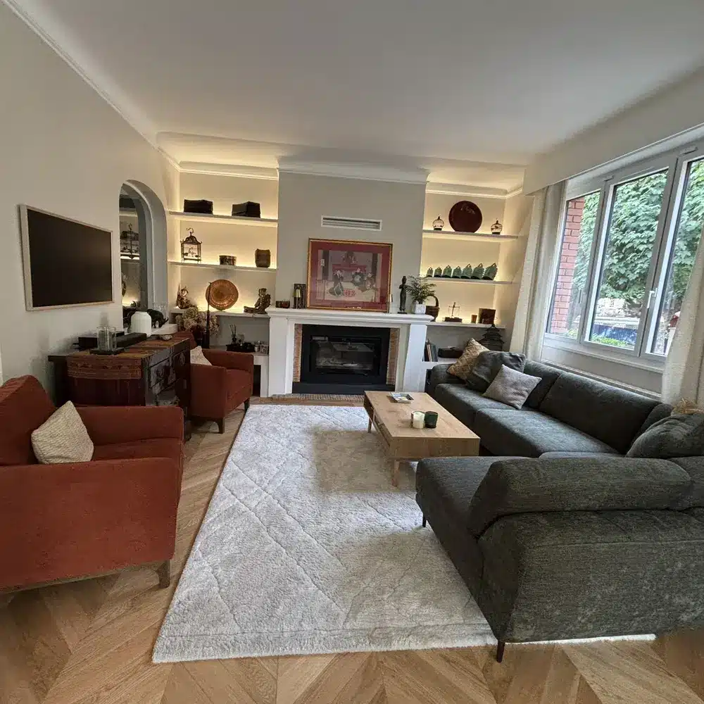 Salon-salle à manger rénové à Saint-Maur : étagères éclairées, fauteuils terracotta et canapé vert